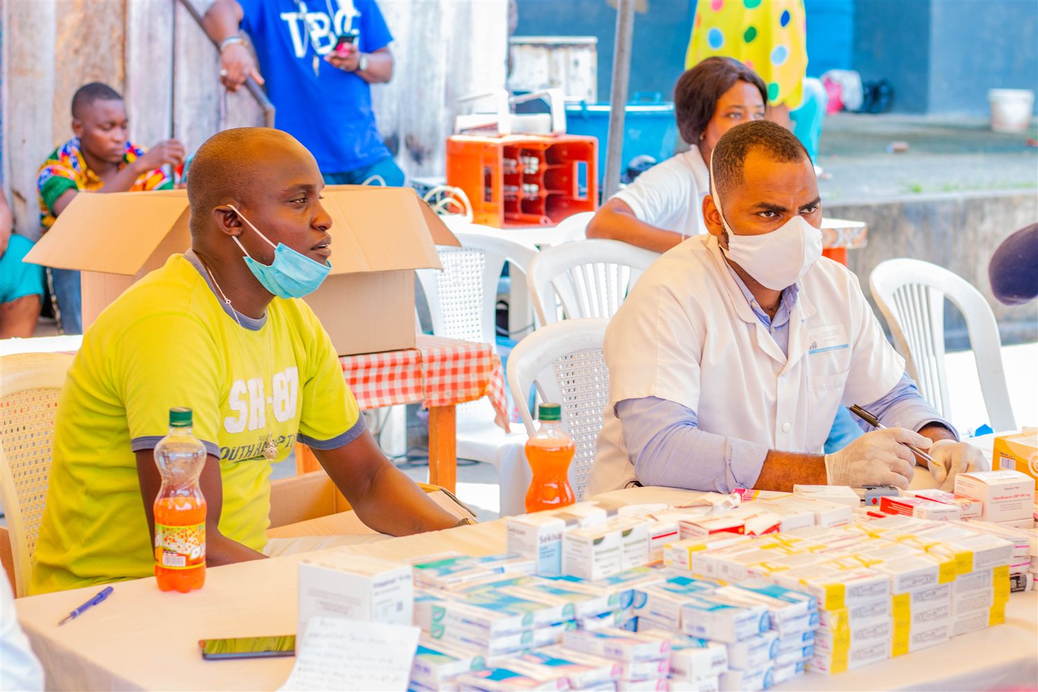 Caravane médicale de NZILA Leaders : un soignant et un bénévole à une table de consultation avec des médicaments